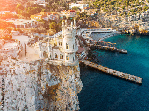 Swallow Nest, ancient castle on top of mountain cliff near sea Yalta region at sunset, Crimea. Beautiful famous palace architecture and amazing nature landscape, aerial view from drone photo