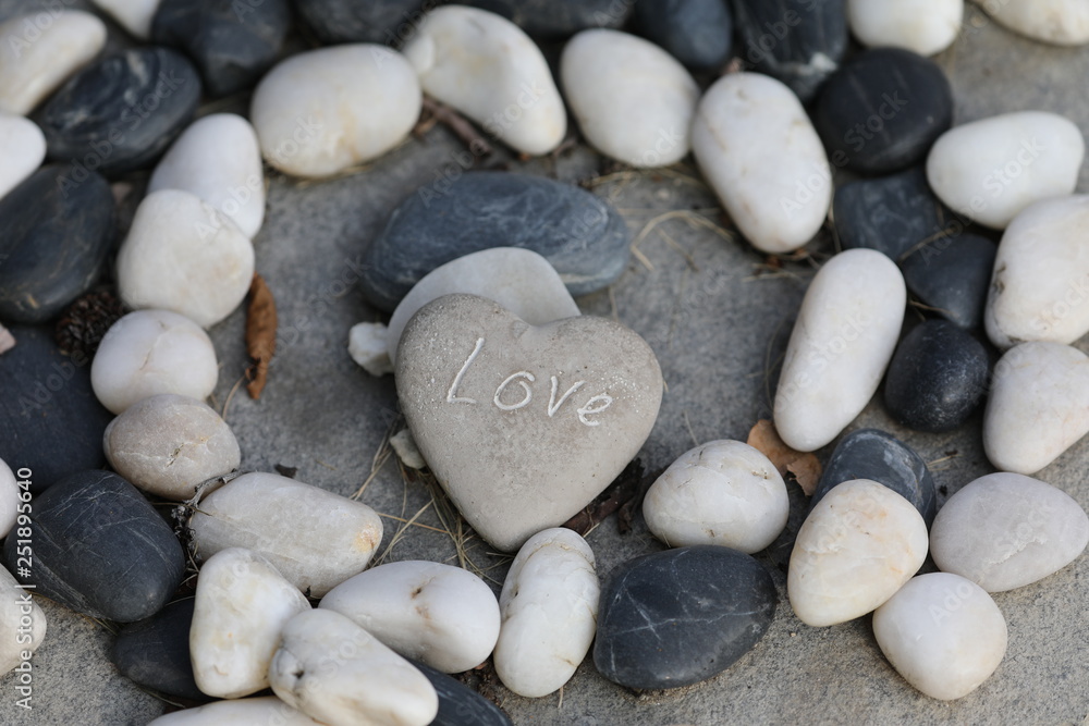close-up view of love inscription on heart-shaped stone and stone circles on grey surface close-up view of love inscription on heart-shaped stone and stone circles on grey surface