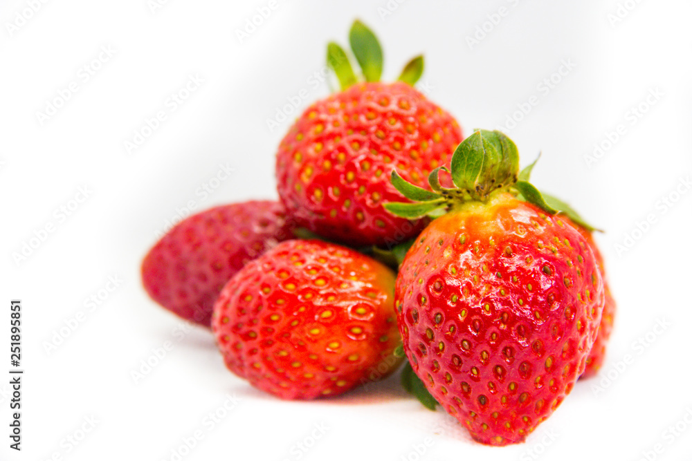 Several red strawberries with leaves on a white background Several red strawberries with leaves on a white background