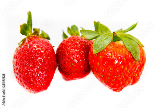 Several red strawberries with leaves on a white background