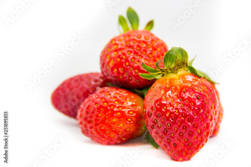 Several red strawberries with leaves on a white background