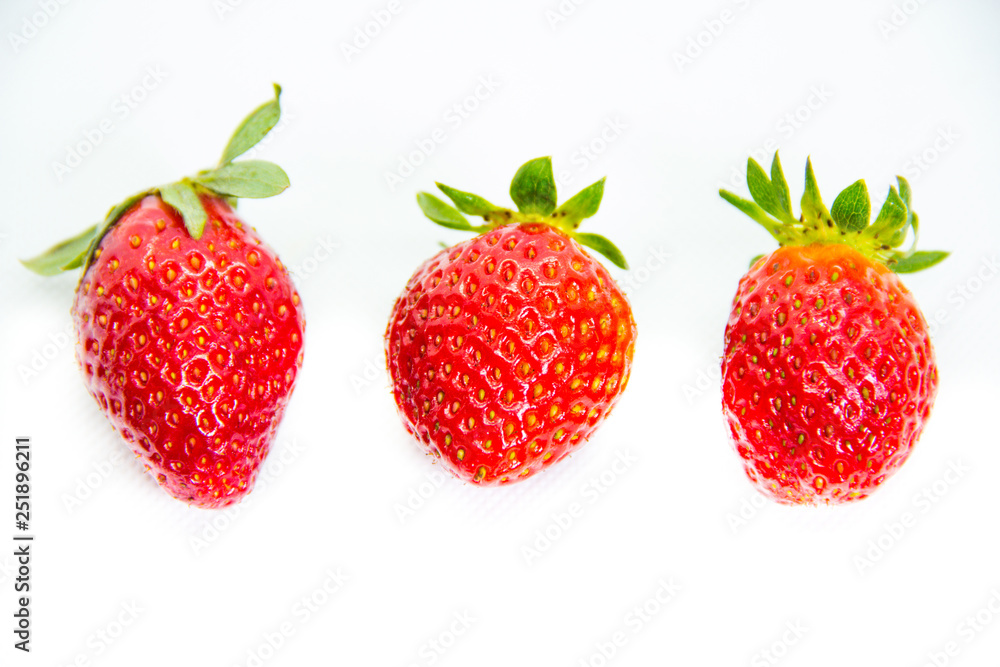 Several red strawberries with leaves on a white background Several red strawberries with leaves on a white background
