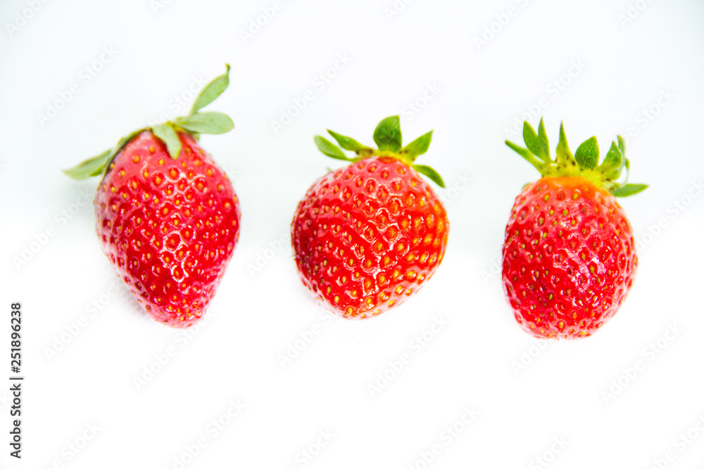 Several red strawberries with leaves on a white background Several red strawberries with leaves on a white background