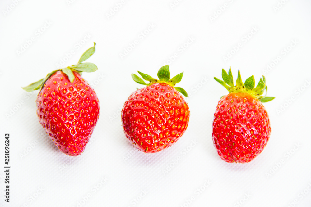 Several red strawberries with leaves on a white background Several red strawberries with leaves on a white background