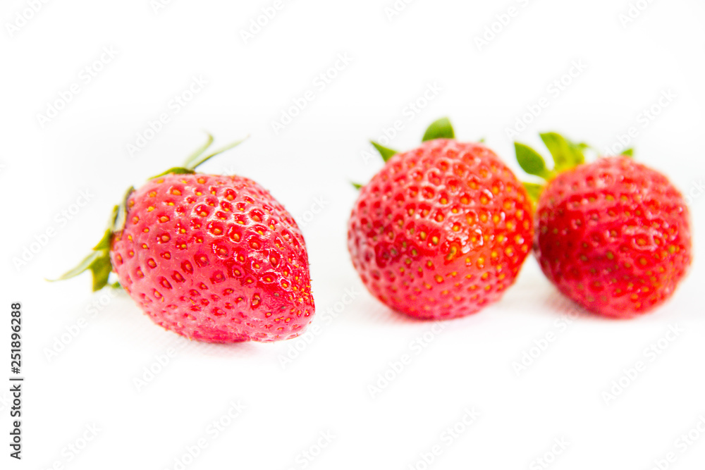 Several red strawberries with leaves on a white background Several red strawberries with leaves on a white background