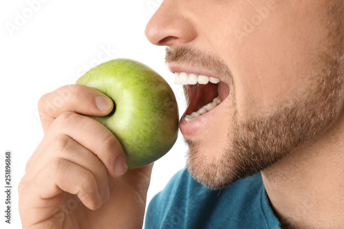 Man with perfect teeth and green apple on white background, closeup