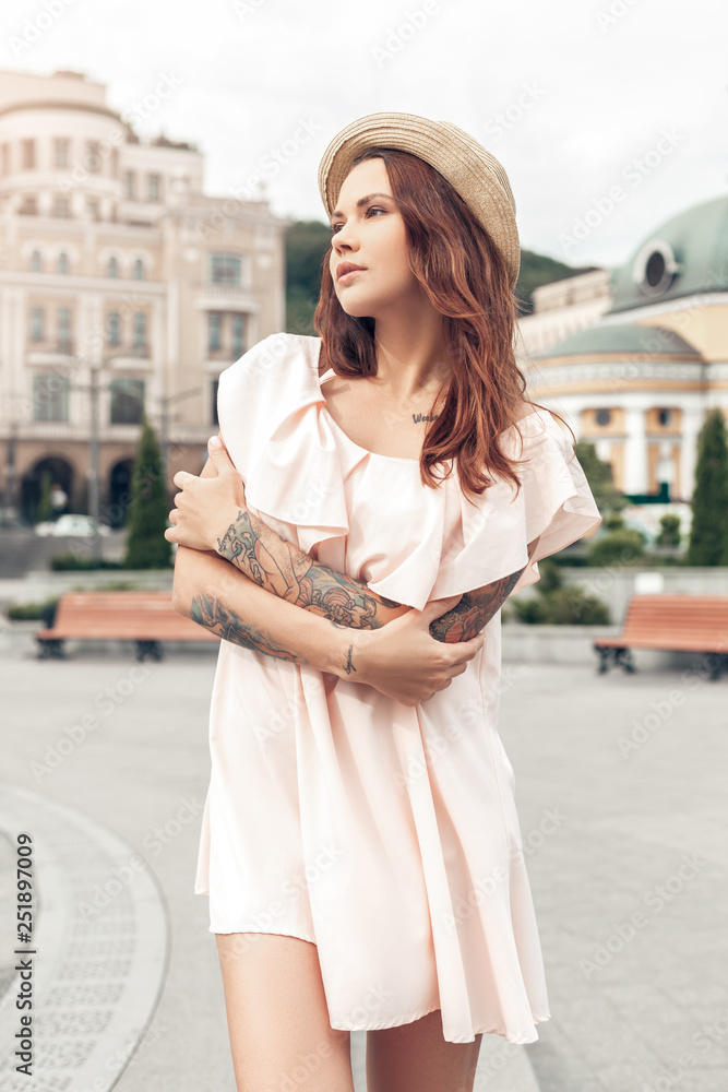 Naklejka premium Ourdoors Leisure. Girl standing on the city street crossed arms looking aside thoughtful