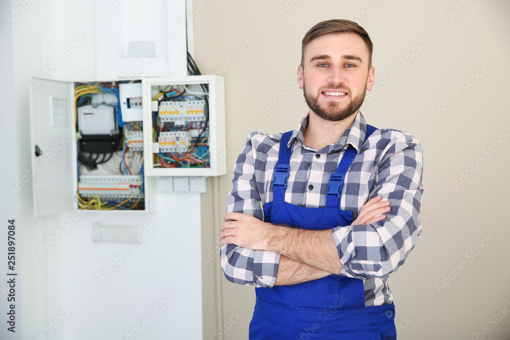 Male electrician standing near fuse board indoors Male electrician standing near fuse board indoors