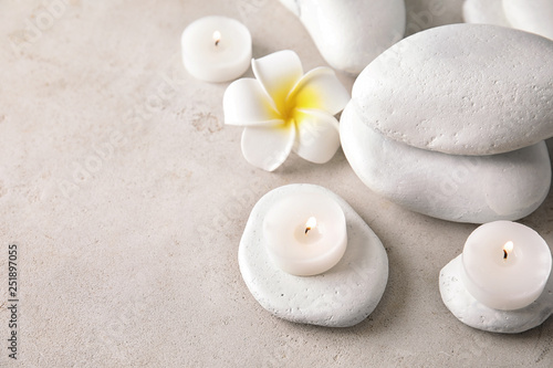 Beautiful spa composition with candles and stones on light background, space for text