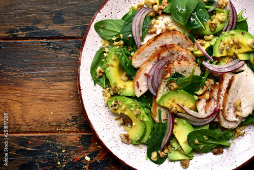 Spinach salad with grilled chicken fillet, avocado and walnuts.Top view with copy space.