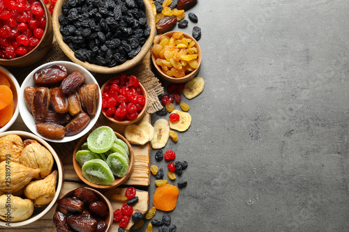 Bowls of different dried fruits on grey background, top view with space for text. Healthy food