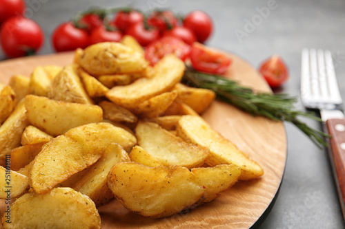 Plate with tasty baked potato wedges on table, closeup © New Africa