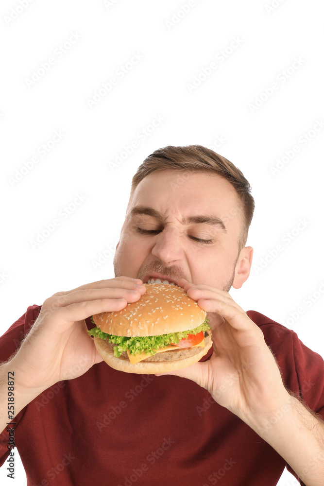 Young man eating tasty burger on white background Young man eating tasty burger on white background