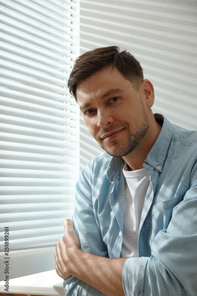 Handsome man near window with Venetian blinds Handsome man near window with Venetian blinds