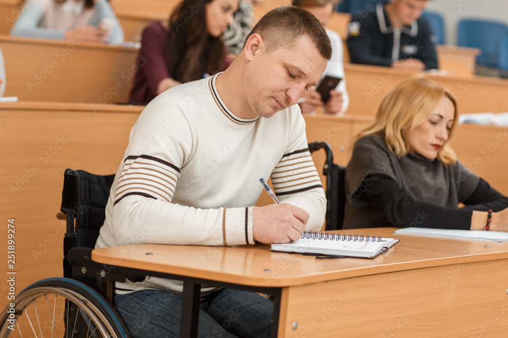 Disable man in wheelchair sitting in lecture hall, listening teacher ...