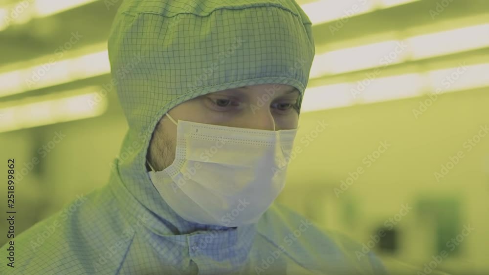 engineer scientist in sterile suits, mask. are in a clean zone looking
