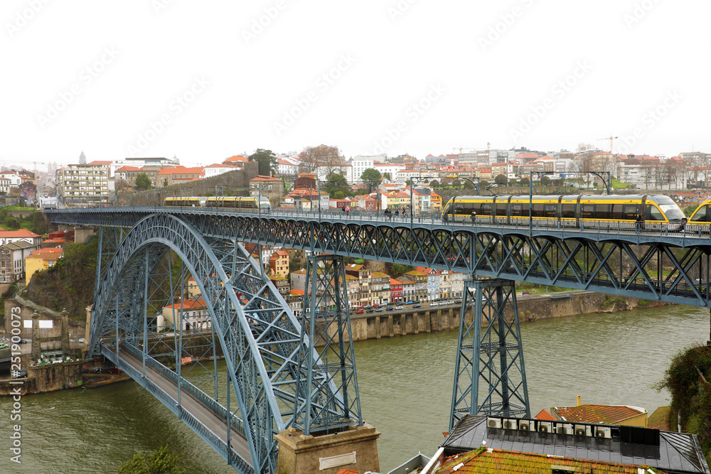 Obraz premium View of the historic city of Porto, Portugal with the Dom Luiz bridge. Two metro train can be seen on the bridge.
