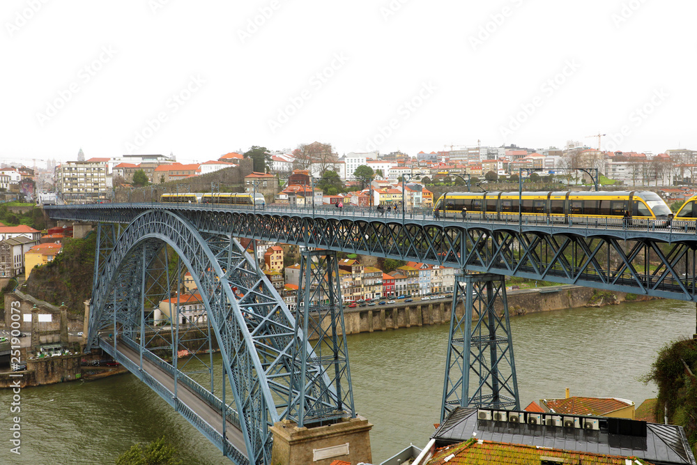 View of the historic city of Porto, Portugal with the Dom Luiz bridge. Two metro train can be seen on the bridge.