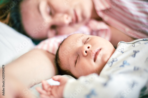 Portrait of newborn baby and mother sleeping on bed, resting together