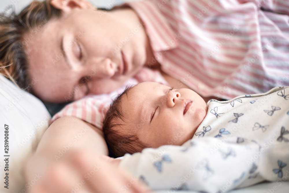 Portrait of newborn baby and mother sleeping on bed, resting together Portrait of newborn baby and mother sleeping on bed, resting together