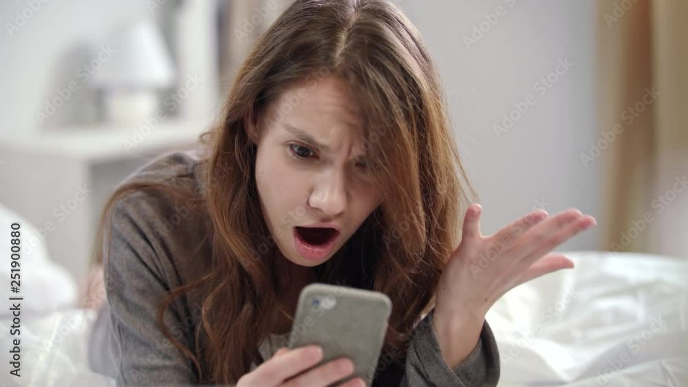 Shocked woman watching video news online on mobile phone at morning Shocked woman watching video news online on mobile phone at morning