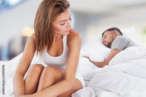 Free Download Dissatisfied beautiful young woman in bed with sad expression on her face, sex problems in long relationship or marriage while man sleeping. Saturation or satiety between caucasian couple, disinterest - GFXLoad