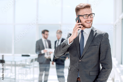 businessman with mobile phone standing next to the Bank office