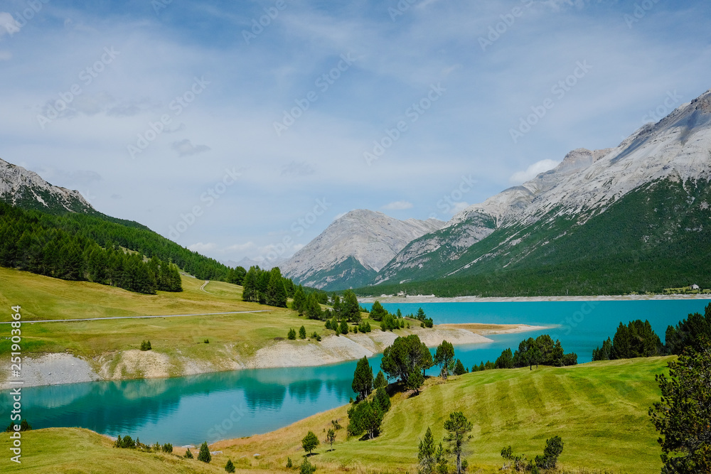 Green mountain lake in Italian Alps Livigno with reflections of the surrounding mountains