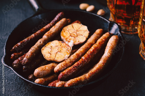beer and snacks. bar table. restaurant, pub, oktoberfest food. two mugs of craft lager and frying pan with delicious homemade grilled sausages. friday party atmosphere, craft brewery concept