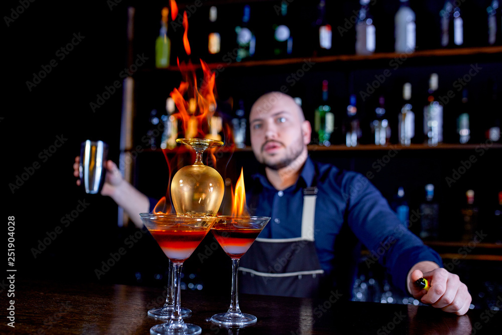 Fiery show at the bar. The bartender makes hot alcoholic cocktail and ignites bar. Bartender prepares a fiery cocktail. Fire on bar.