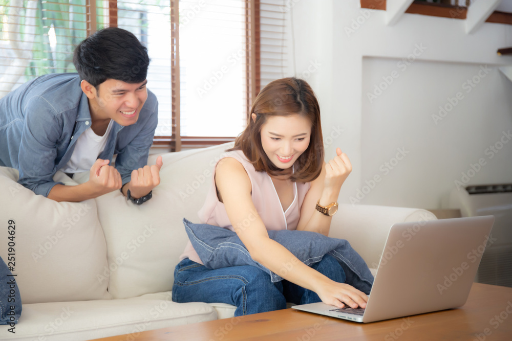 Beautiful portrait asian young couple working laptop with smile and happy sitting on couch at living room, man and woman on sofa using notebook computer with excited, business and success concept. Beautiful portrait asian young couple working laptop with smile and happy sitting on couch at living room, man and woman on sofa using notebook computer with excited, business and success concept.