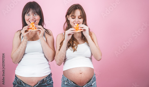 nutrition concept, pregnant women eating pizza on a pink background photo