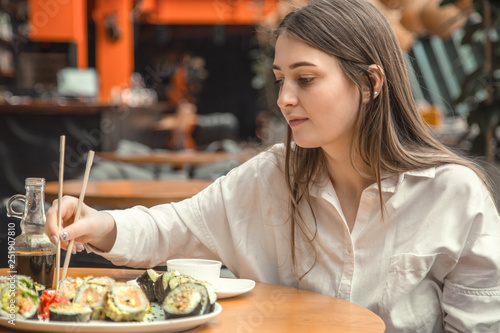 Young Woman eating and enjoying fresh sushi