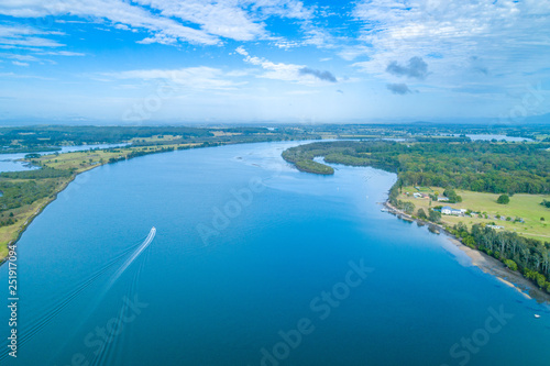 Aerial landscape of boat sailing on the Manning River leaving water trail