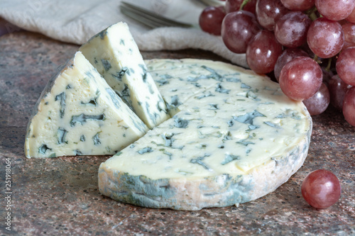 Fourme Ambert semi-hard French blue cheese made from raw cow milk served as dessert with grapes photo