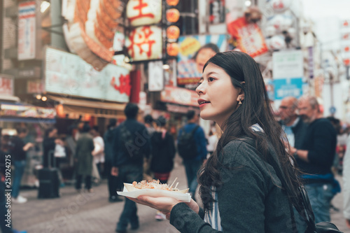 Bilde på lerret vintage photo of young girl tourist standing on dotonbori street outdoor holding local specialty snack