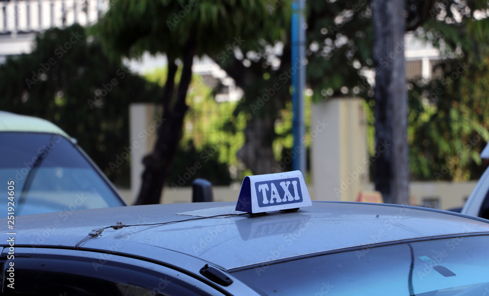 Taxi light sign or cab sign in white and blue color with white text on the car roof at the street.