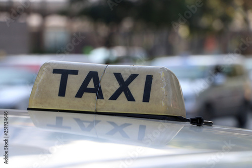 Taxi light sign or cab sign in brown color with black text and tied with wire on the car roof at the street.