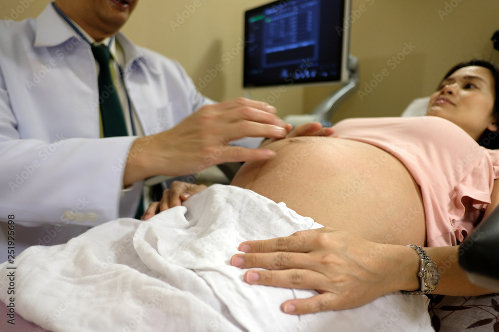 Asian pregnancy woman lying on the chair is listening carefully to the maternity doctor explaining about her baby movement in tummy before making an ultrasound check. Mother healthcare concept. Asian pregnancy woman lying on the chair is listening carefully to the maternity doctor explaining about her baby movement in tummy before making an ultrasound check. Mother healthcare concept.
