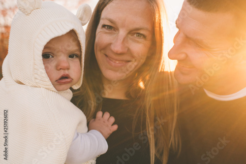 Mother and Father holding daughter at sunset