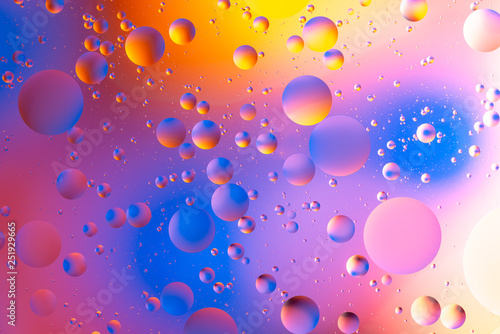 purple and orange oily drops  in water with colorful background  close-up 