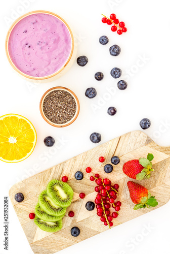 Preparing healthy fruit smoothie. Acai smoothie bowl near cutting board with fresh fruits, berries, chia seeds on white background top view