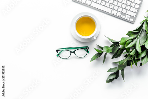 Spring inspiration. Office work desk with computer keyboard, glasses, fresh green spring leaves on white background top view copy space