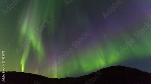 Northern, aurora borealis in the sky above the hills. Violet and green. Color. © Moroshka