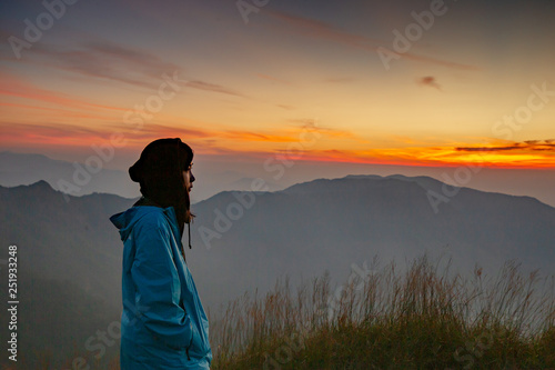 Woman waiting for sunrise at Sanknokwua (San Knok Wua) hill at Khao Laem National Park, Kanchanaburi, Thailand. Abstract of freedom and Peaceful with natural clear sky background photo