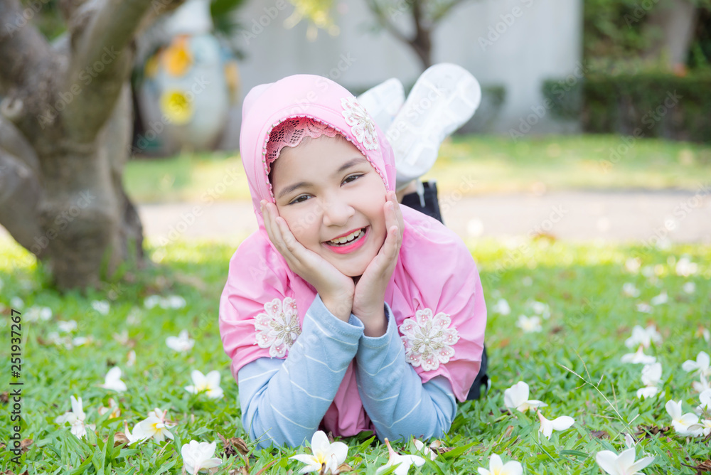 Pretty muslim girl lying on grass under a tree and smiles. Pretty muslim girl lying on grass under a tree and smiles.