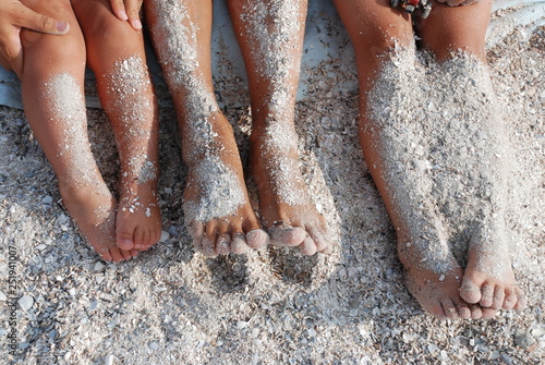 children's tanned legs in the sand on the beach