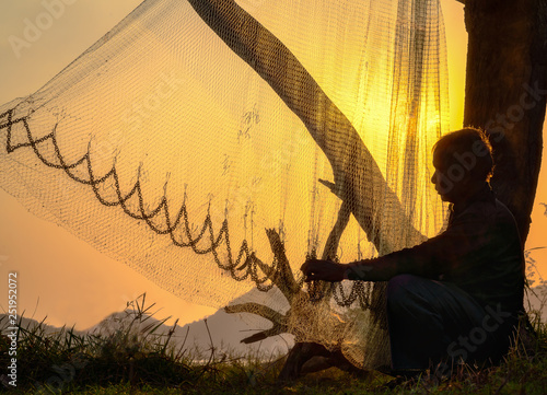 Fisherman repairing fishing net at sunset. photo