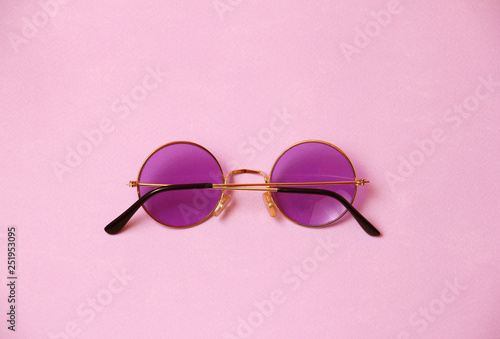 single transparent round pink purple glasses on uniform coral background, temple arm of eyeglasses are closed, back view
