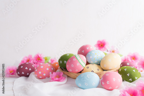 Happy easter! Colorful of Easter eggs in nest with flower and Feather on white cheesecloth background.